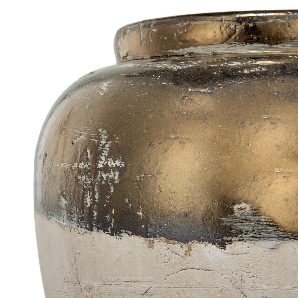 Close-up of a weathered, metallic-gold and beige ceramic vase.