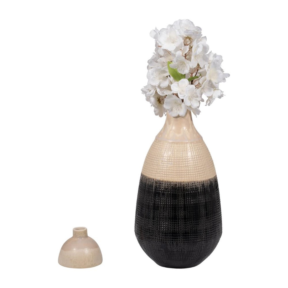 Black and beige vase with white flowers, additional lid beside.
