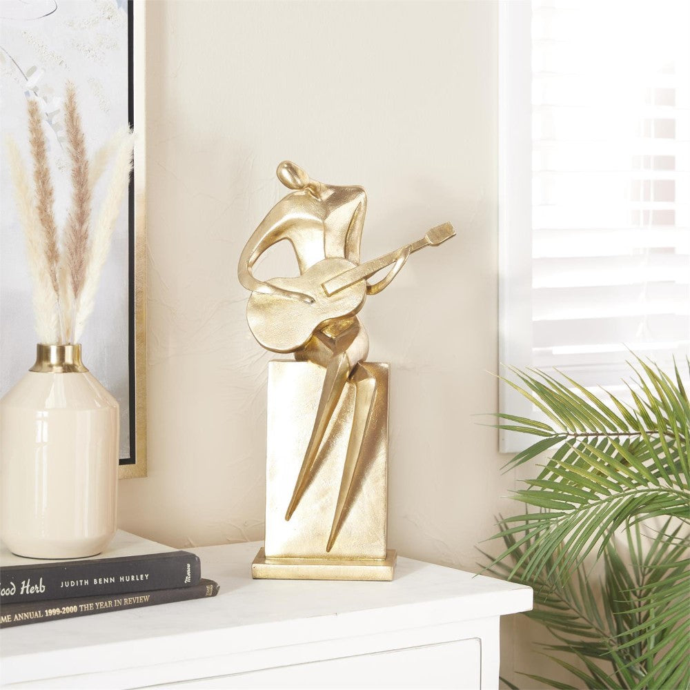 Gold abstract musician sculpture on a white shelf.