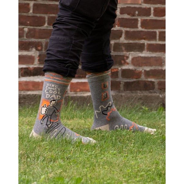 Person wearing fun "Cool Dad" socks standing on grass.