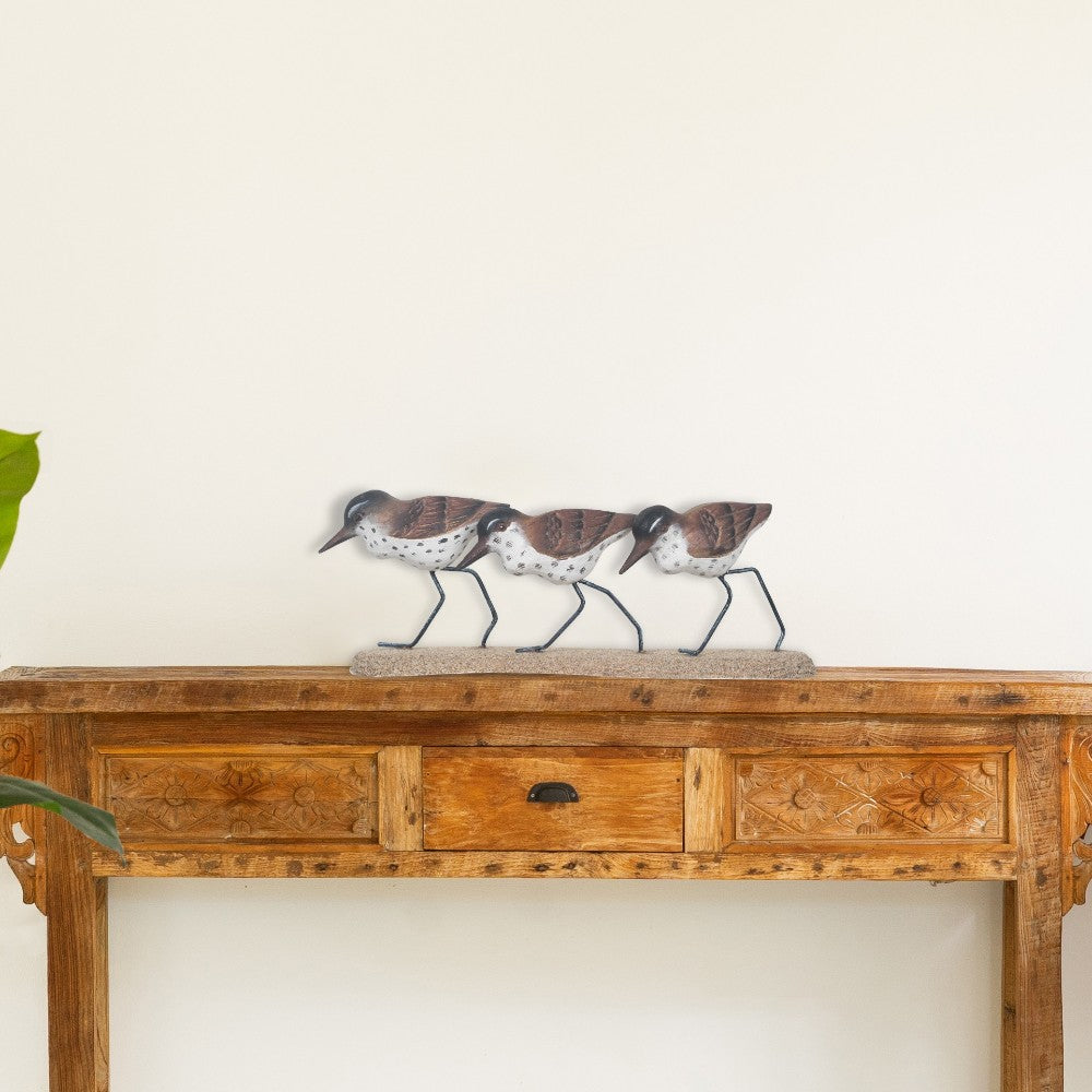 Wooden console with bird figurines on top.
