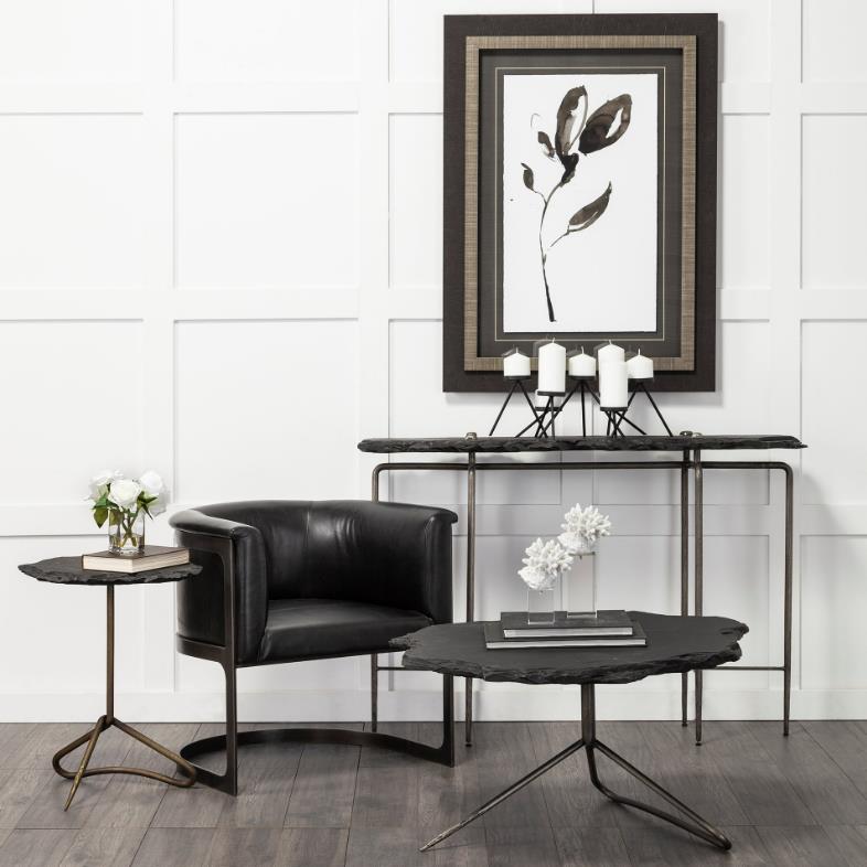 Modern seating area with black chair, tables, candles, and abstract art.
