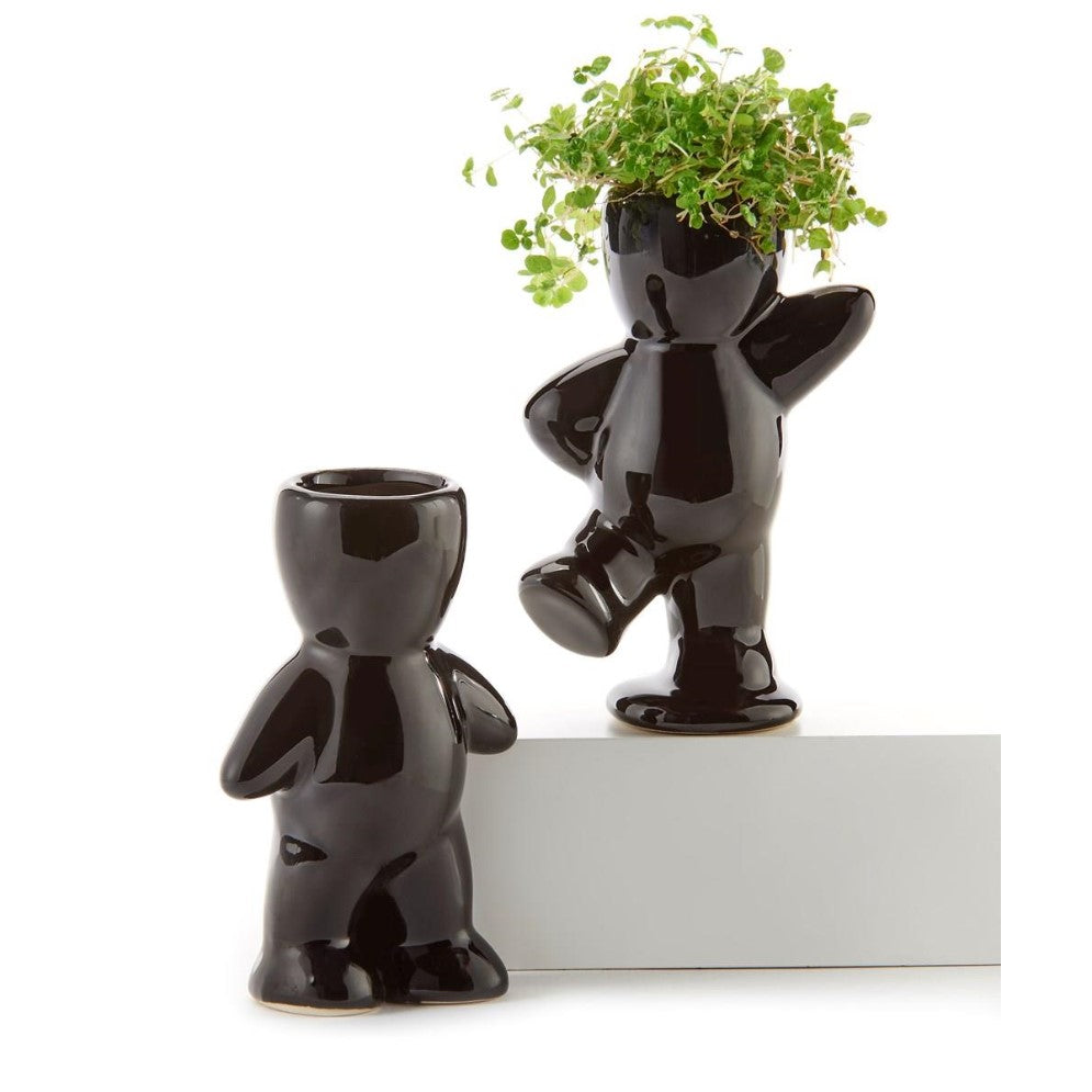 Two black ceramic figure planters, one with green plant hair.