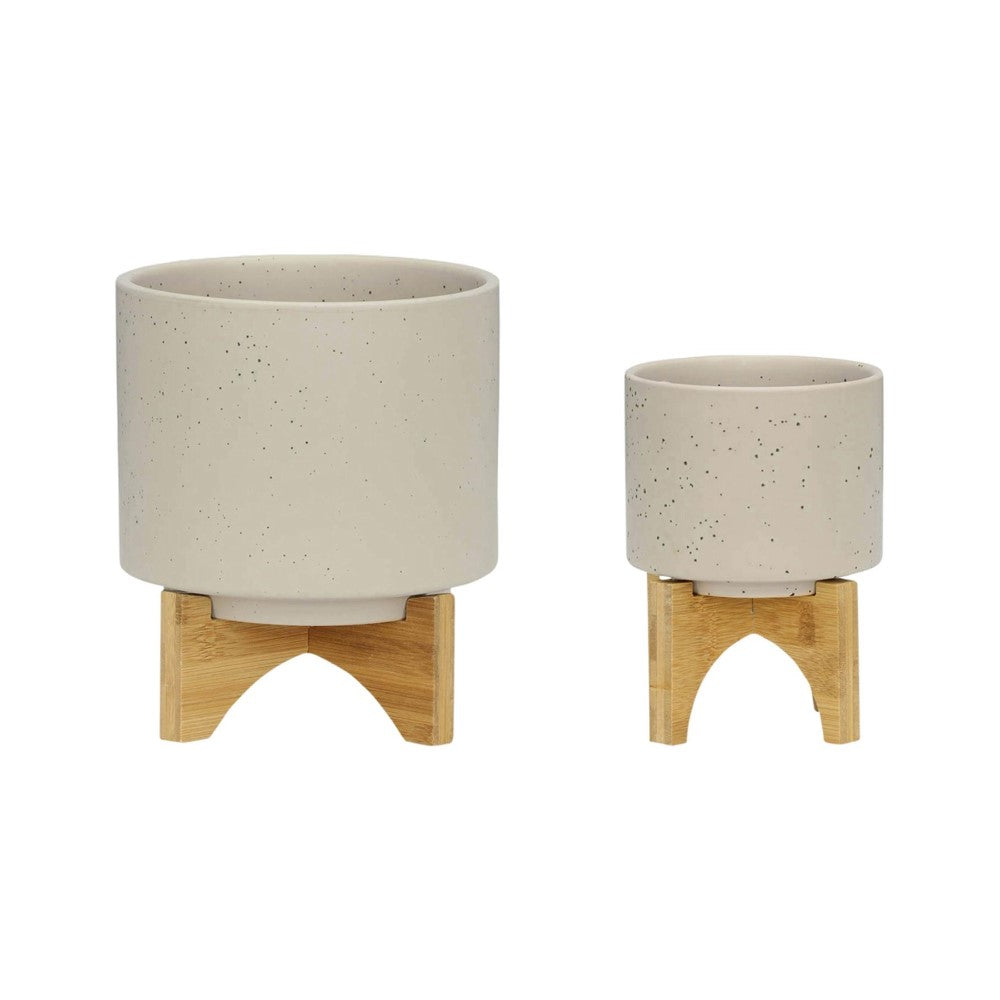 Two speckled ceramic pots on wooden stands, one large, one small.