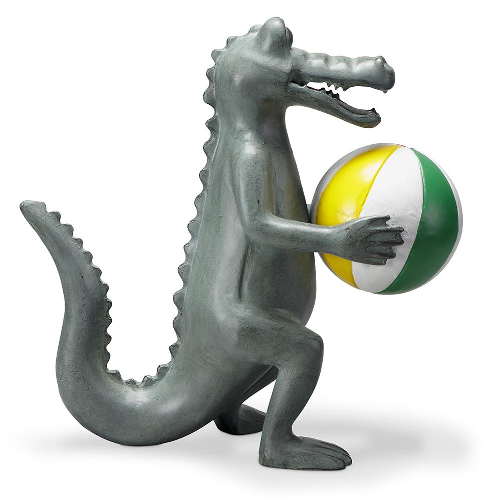 Metal alligator statue holding a yellow and green ball.