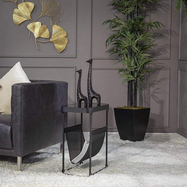 Elegant room with modern decor, black sofa, plant, sculptures, and gold wall art.