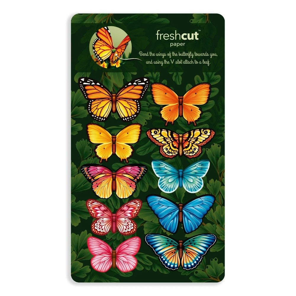 Colorful paper butterflies on green leafy background.