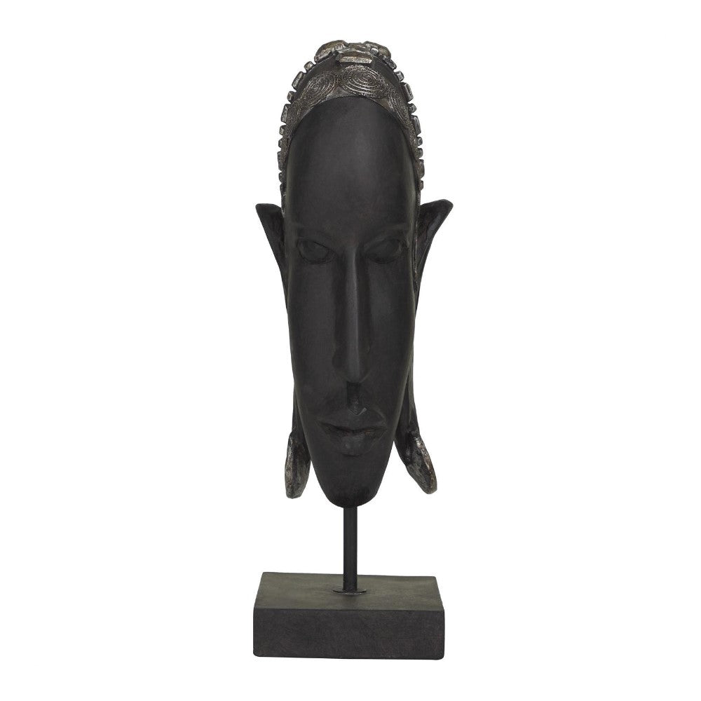 Dark, elongated mask sculpture on a stand.