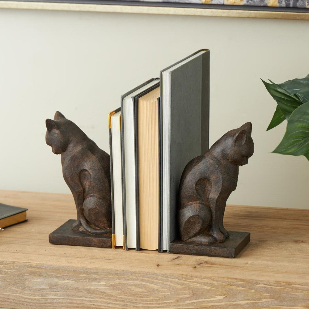 Cat bookends holding a row of books on a wooden shelf.