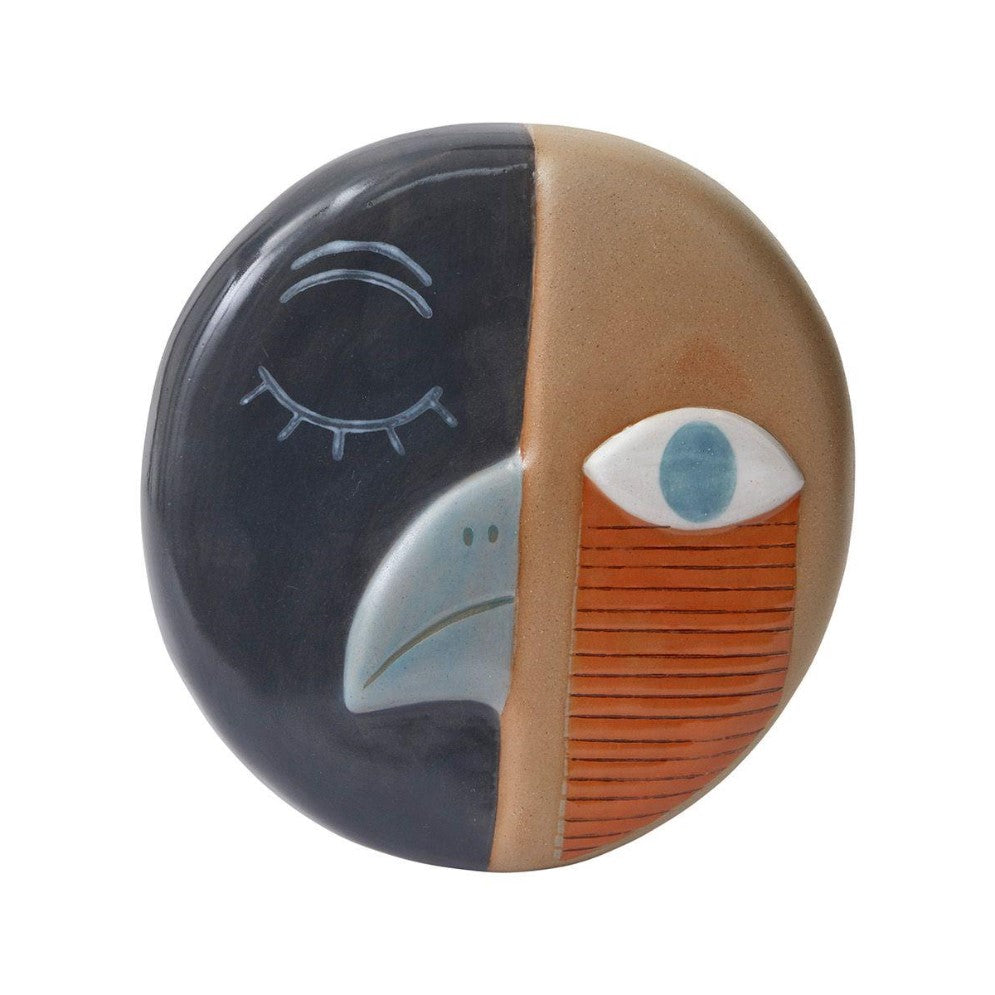 Abstract ceramic face with contrasting colors and geometric features.