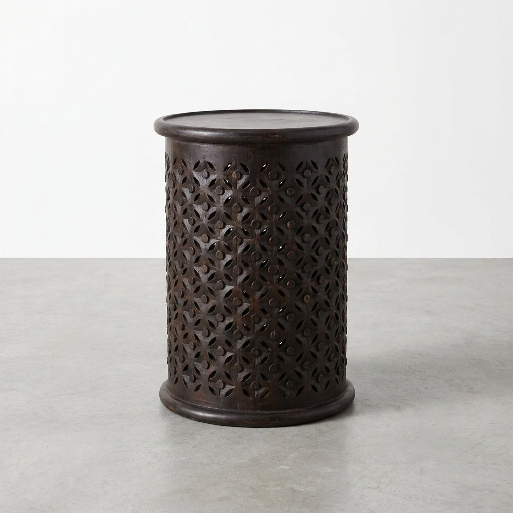 Black cylindrical stool with intricate cut-out pattern.