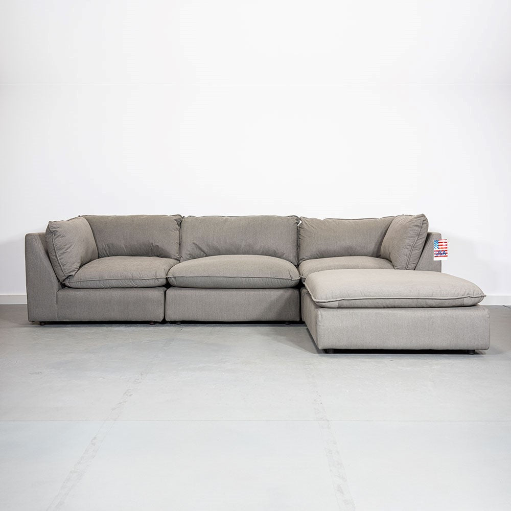 Gray sectional sofa on a light floor in front of a white wall.