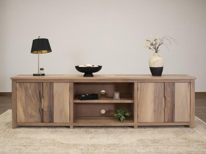 Wooden sideboard with decor: lamp, bowl, and vase on top, greenery on the shelf.