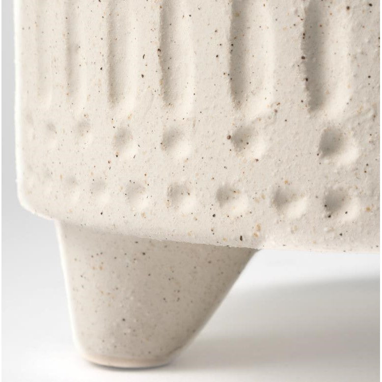 Close-up of a textured ceramic pot with speckled pattern and tapered leg.