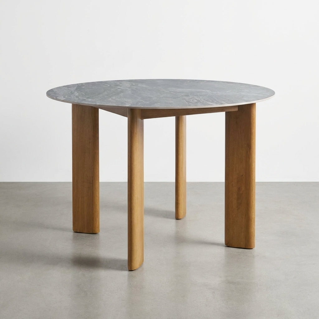 Round table with a marble top and wooden legs on a gray floor.