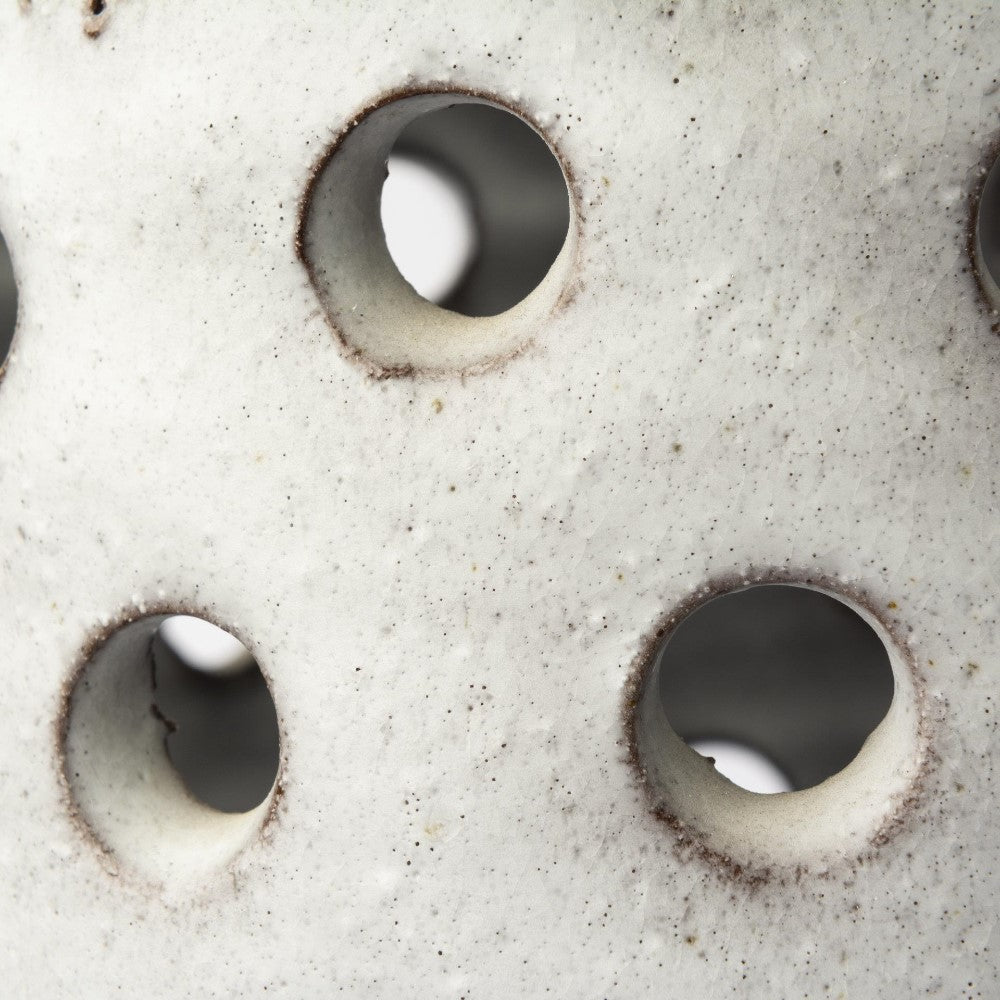 Close-up of a porous, white textured surface with circular holes.