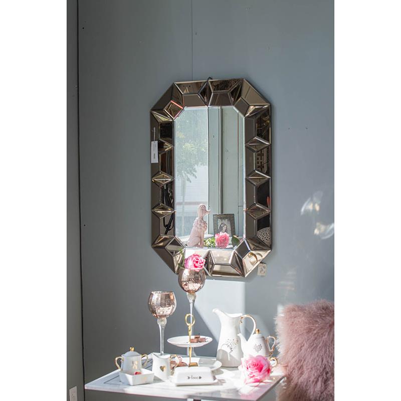 Elegant decor with a geometric mirror, ceramics, and pink roses.