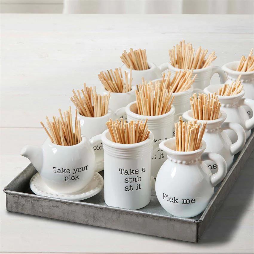 Ceramic holders with toothpicks, each with a playful message.