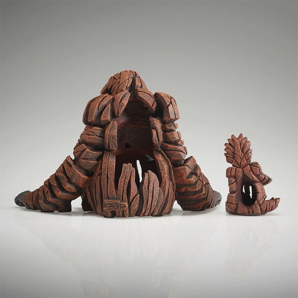 Wooden sculptures resembling abstract, organic forms on a reflective surface.