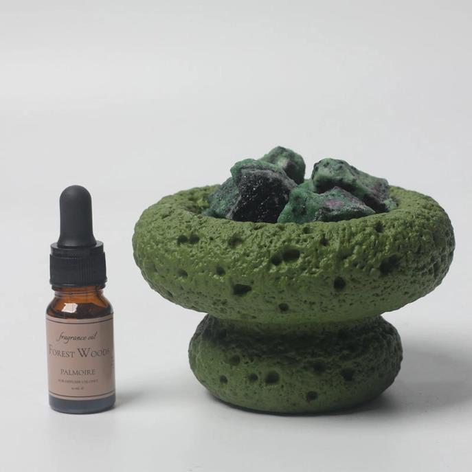 Fragrance oil next to a green stone holder with rocks.