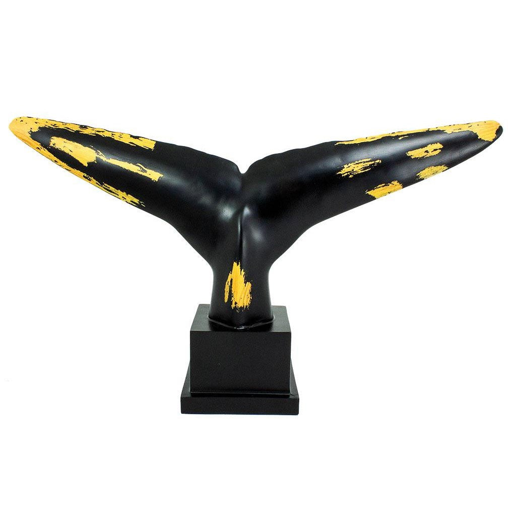 Black and gold whale tail sculpture on a base.
