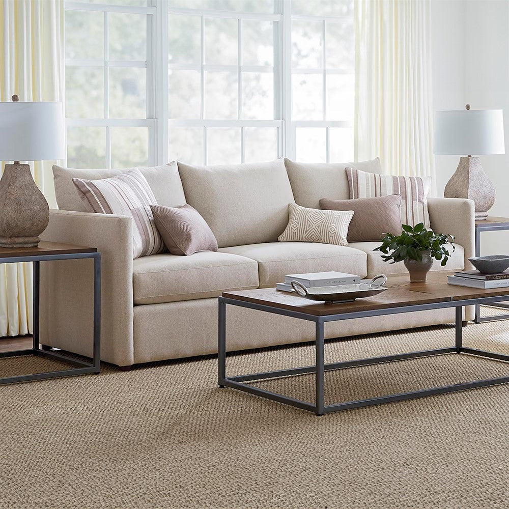 Bright living room with beige sofa, coffee table, and large windows.