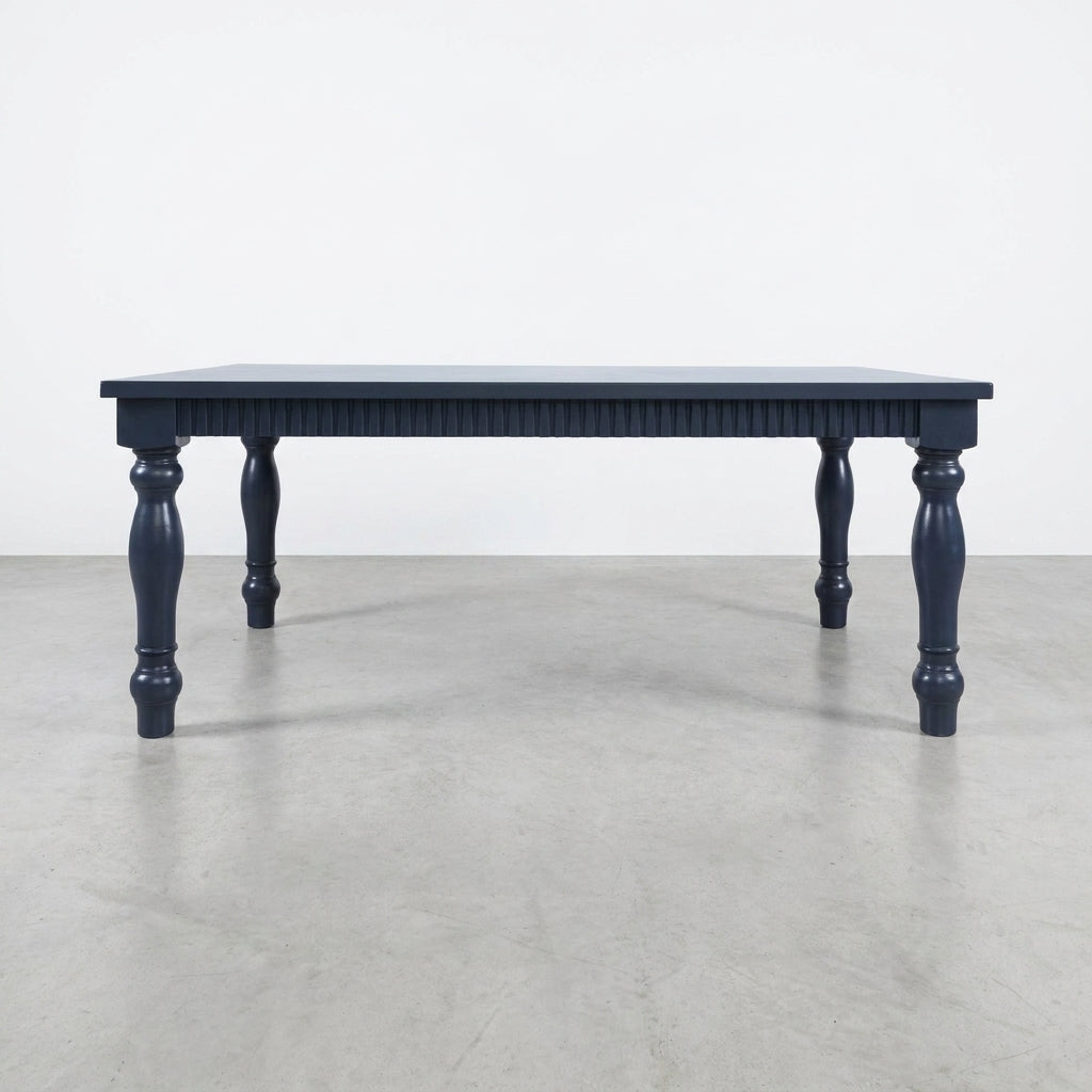Dark blue table with carved legs on a concrete floor.