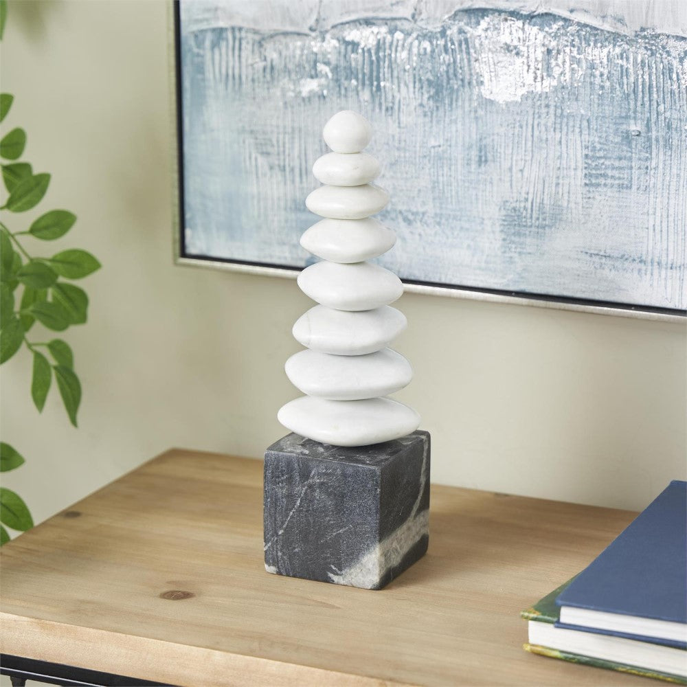 Stacked white stones on a wooden table beside books.