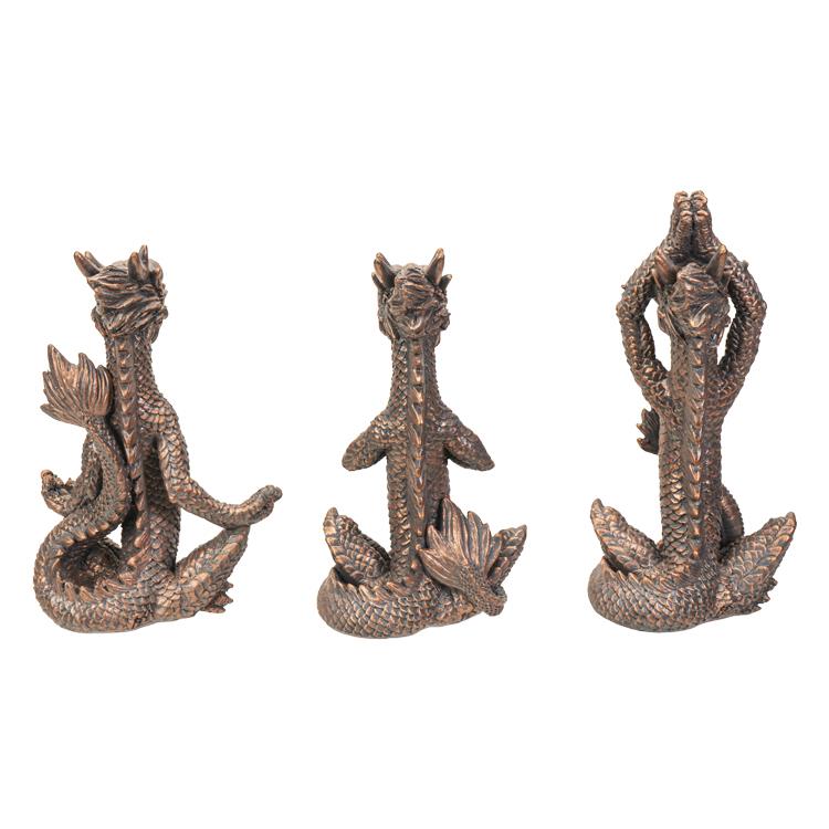 Three bronze dragon figures sitting in yoga poses.