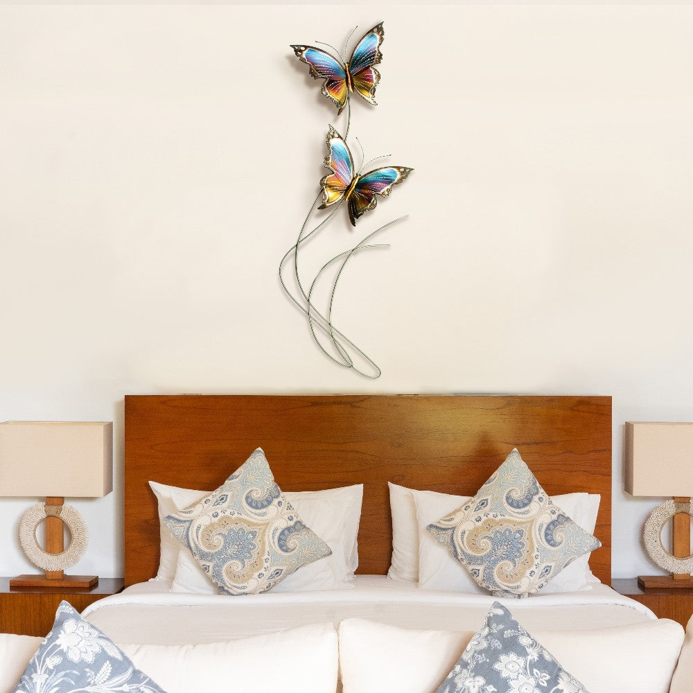 Bedroom with butterfly wall art above a bed and decorative pillows.