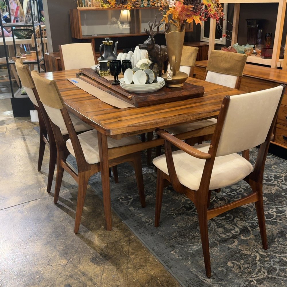 Wooden dining table with beige chairs and decorative centerpiece.