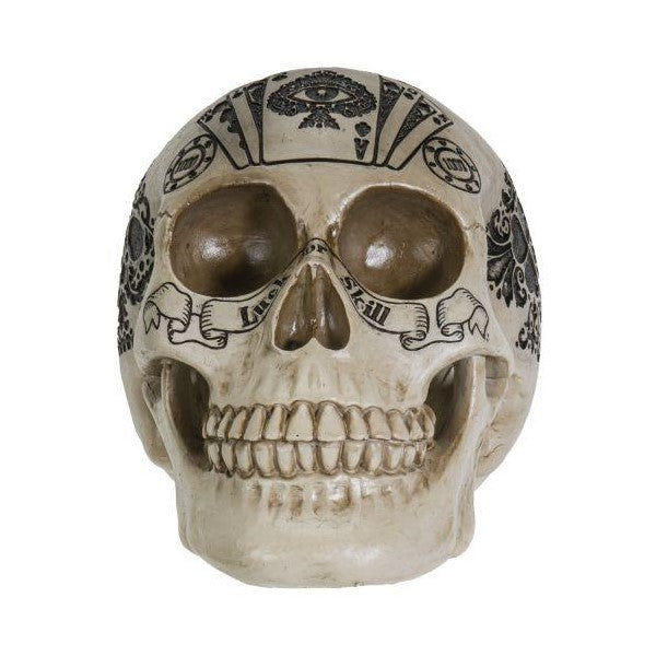 Decorative skull with intricate black designs and a scroll across the teeth.