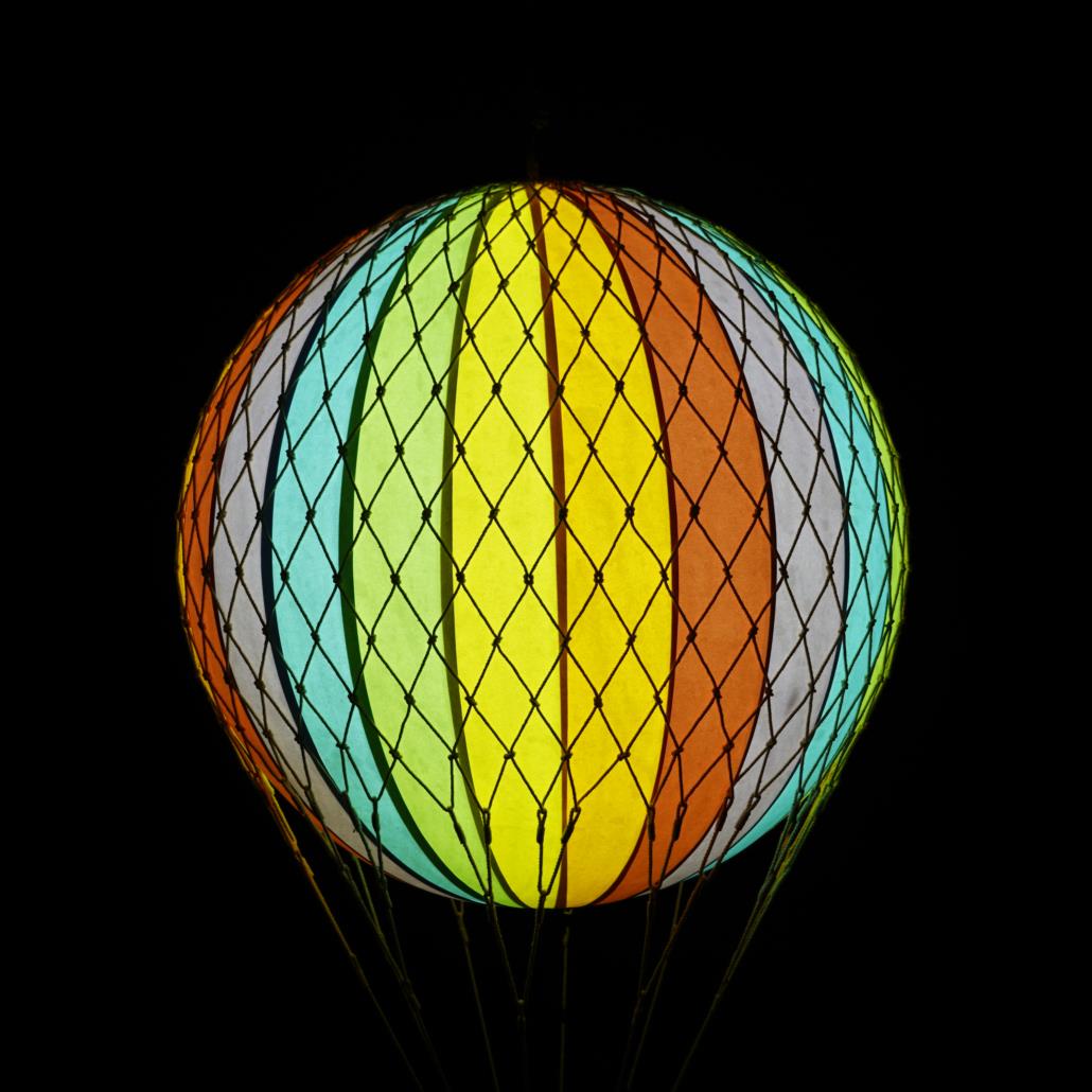 Colorful striped hot air balloon against a black background.