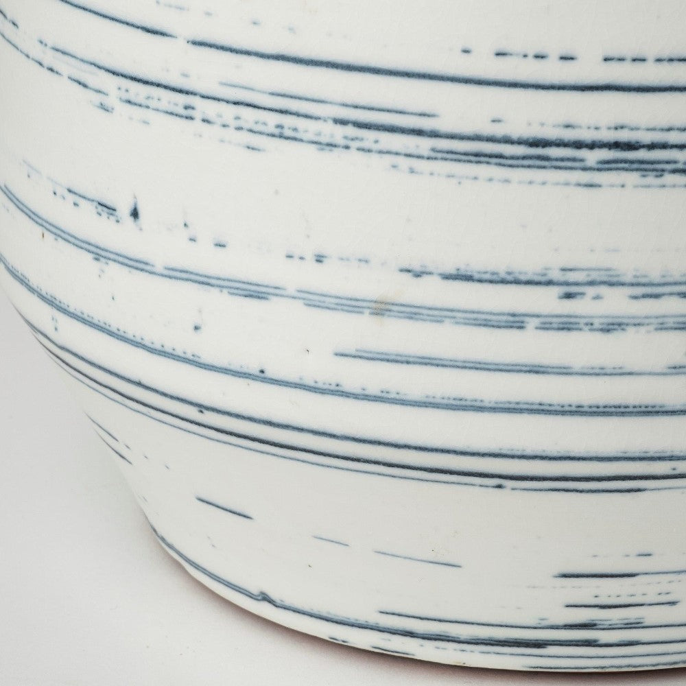 Ceramic with blue parallel line patterns on a white background.