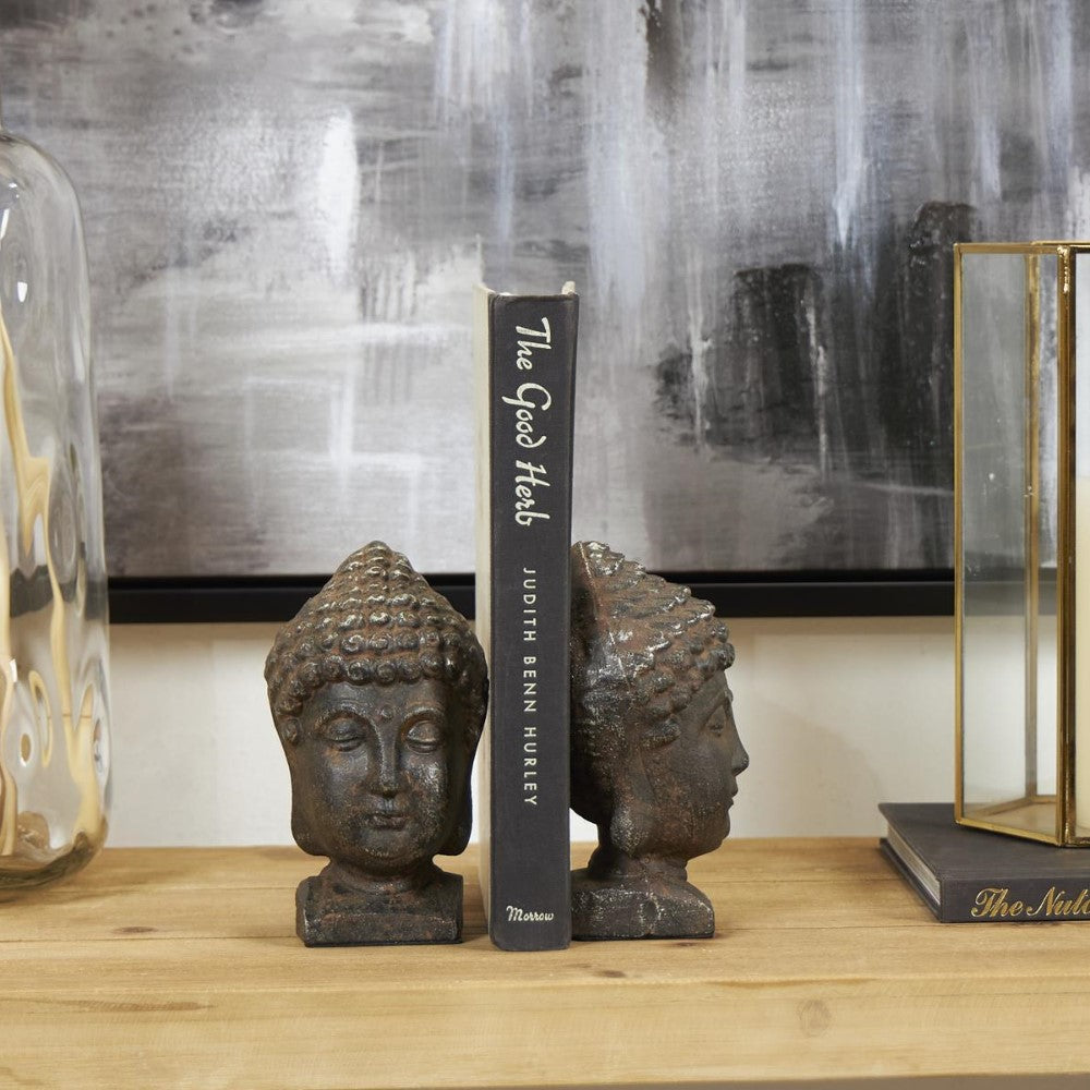 Book with Buddha head bookends on a wooden shelf.
