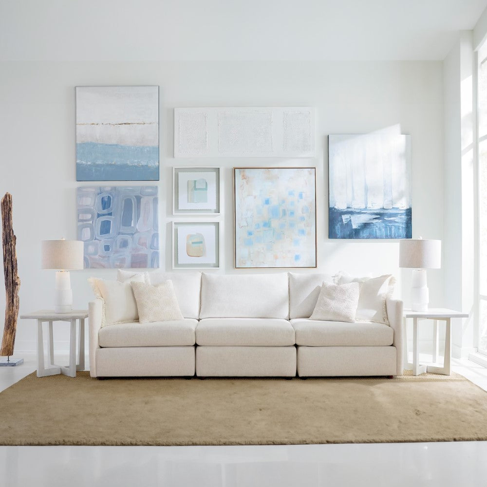 Bright living room with white sofa, abstract art, and soft lighting.