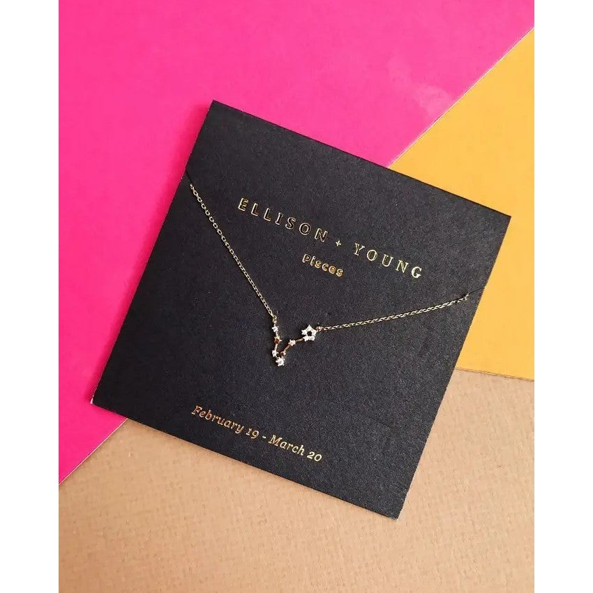 Necklace on black card with constellation design, bright pink and orange background.