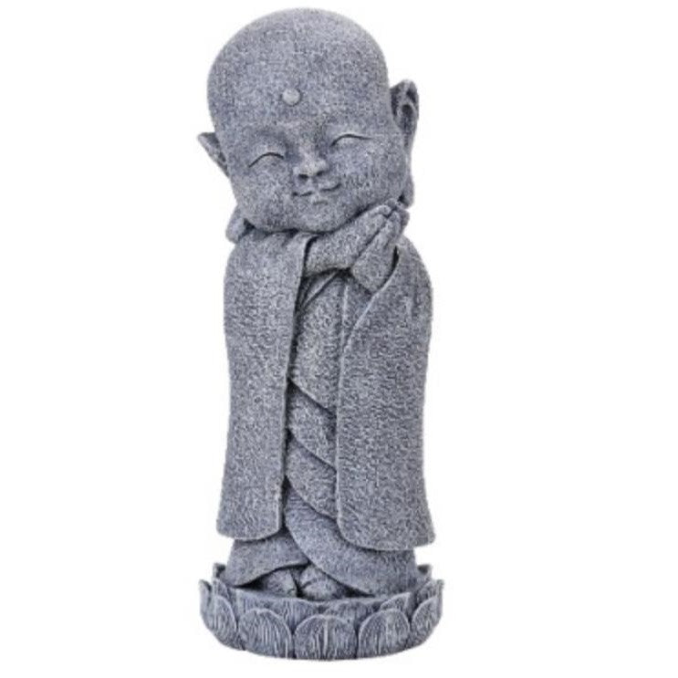 Stone statue of a serene, smiling monk with hands folded.