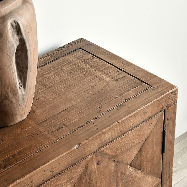 Rustic wooden cabinet with a carved vase on top.