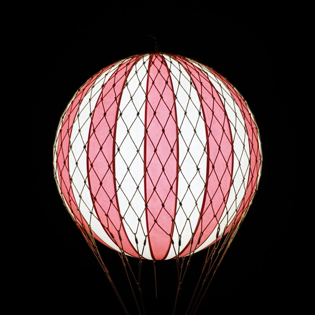 Red and white balloon with netting, dark background.