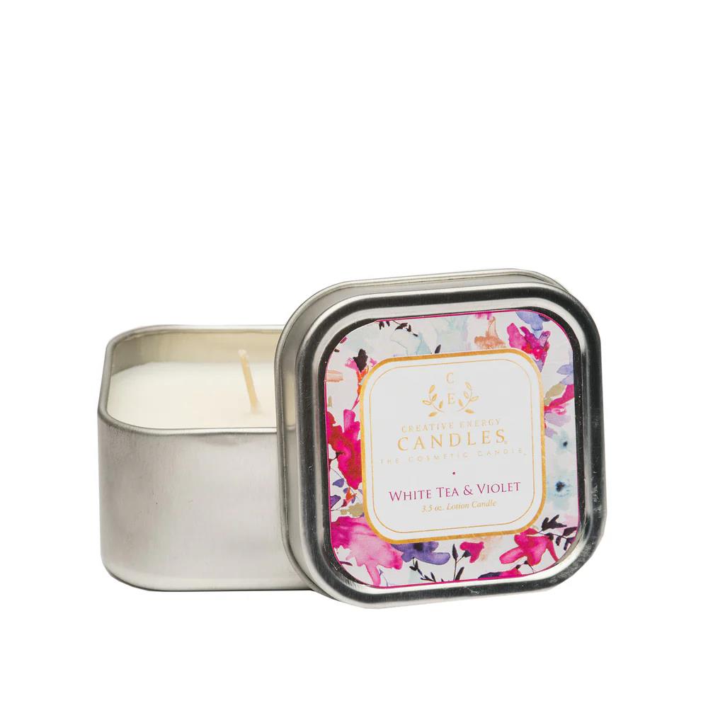 Square tin candle labeled "White Tea & Violet," with floral design.