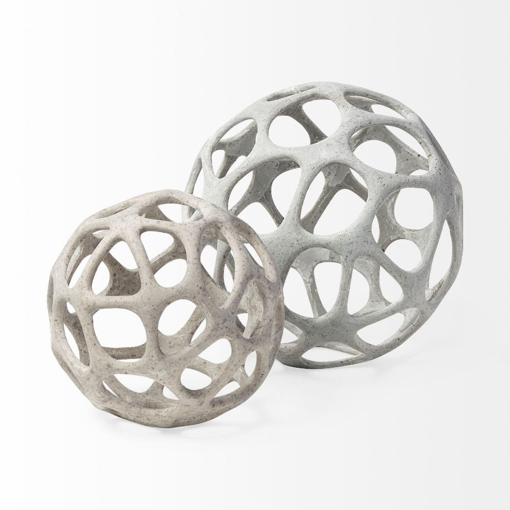 Two openwork spherical sculptures, gray and beige, on a white background.