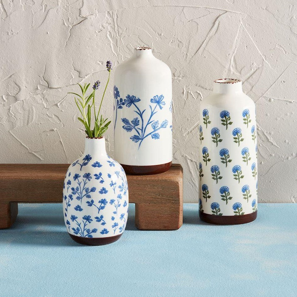 Three white vases with blue floral patterns on a wooden stand.