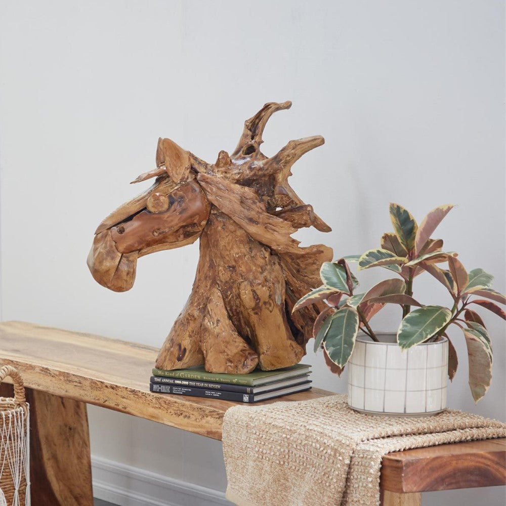 Wooden horse sculpture on a table with plant and books.