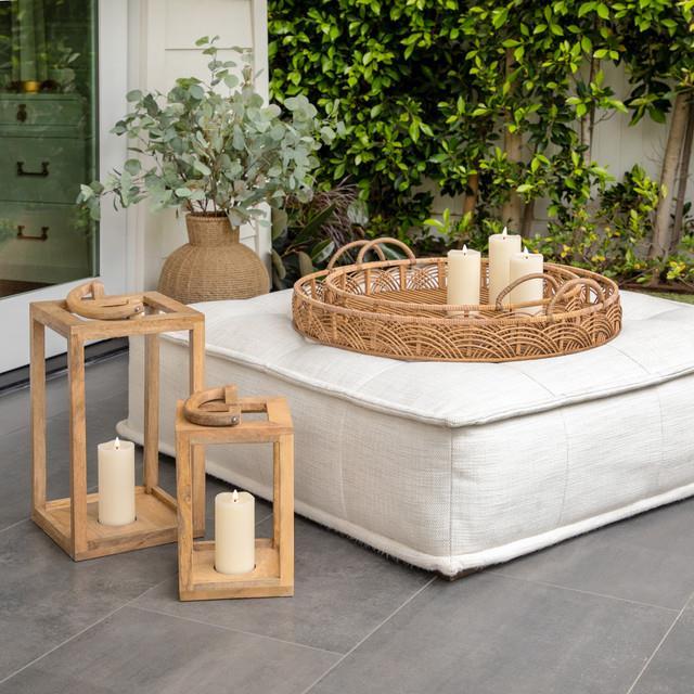 Cozy patio with candles, wicker tray, and leafy plants.