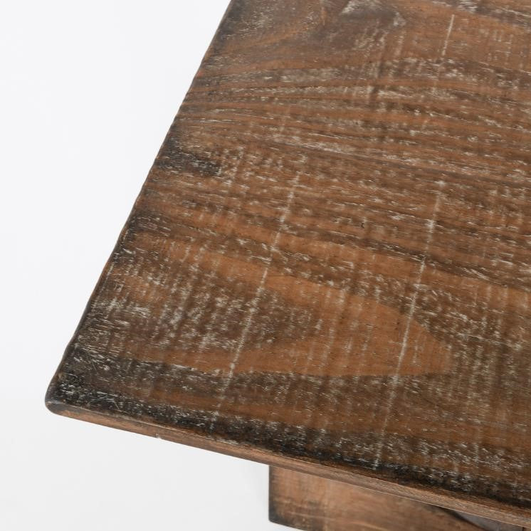 Close-up of a wooden table corner with a rustic finish.