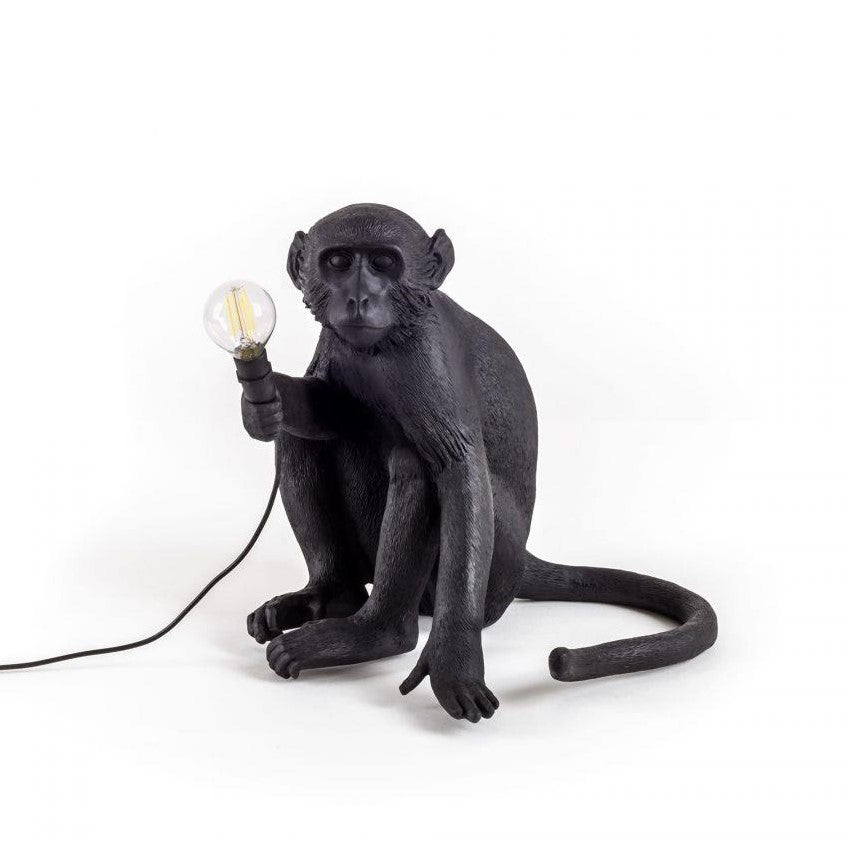 Monkey lamp with black finish holds a light bulb.