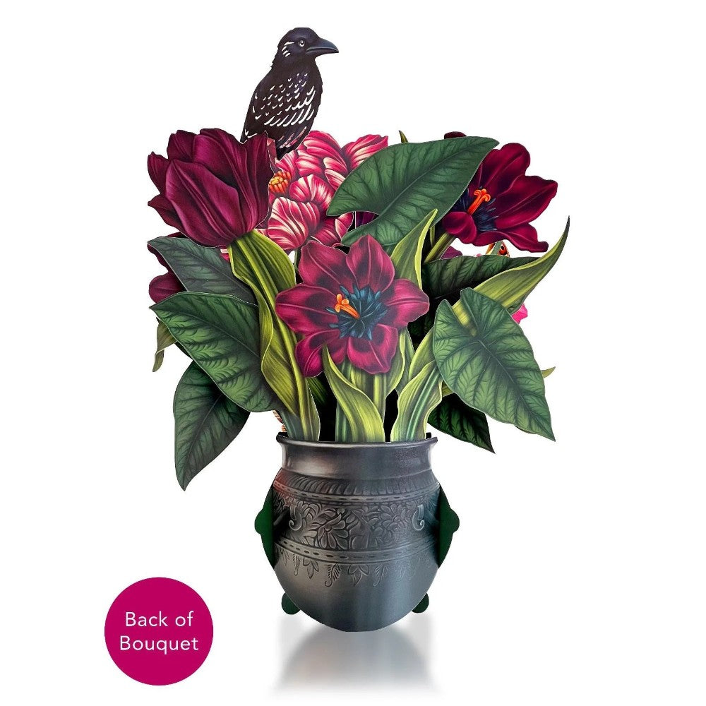 Paper bird perched on vibrant floral arrangement in an ornate pot.