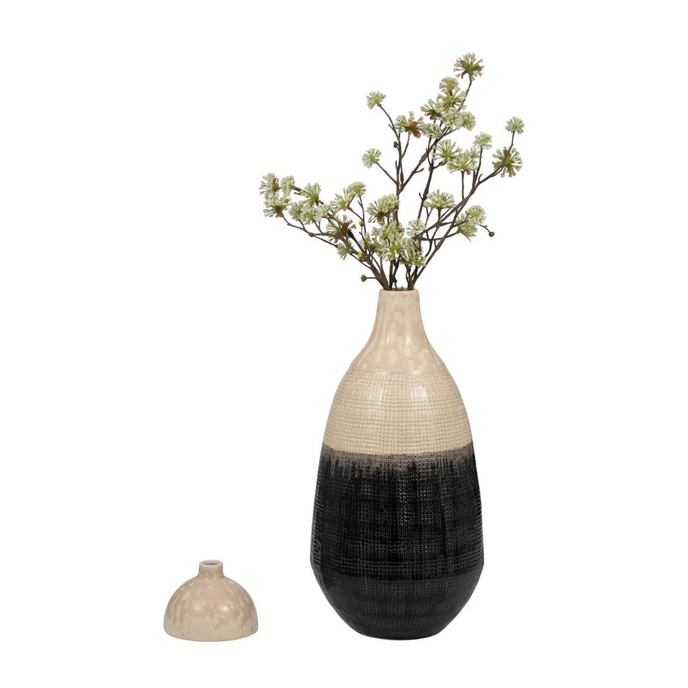 Two-tone vase with flowers, detached lid nearby.