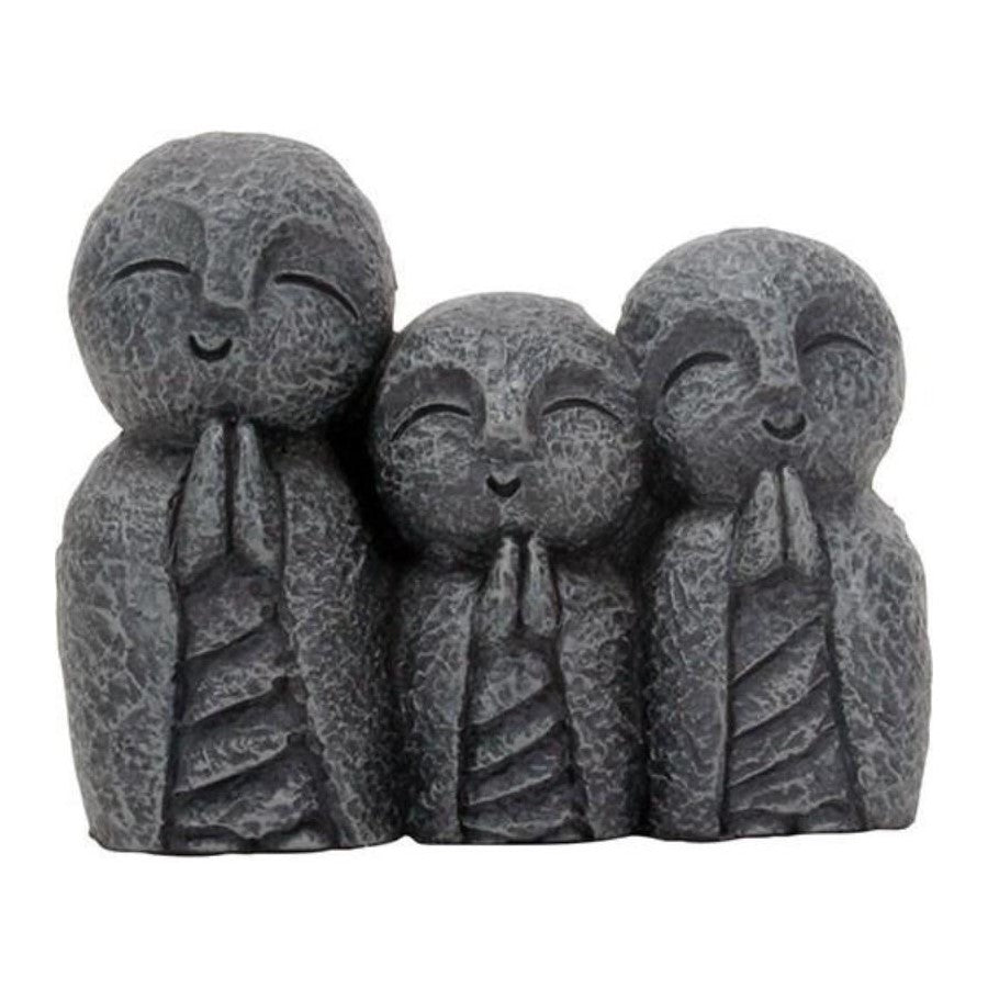 Three smiling stone statuettes with closed eyes and folded hands.